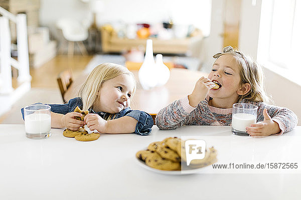 Mädchen essen Milch und Kekse