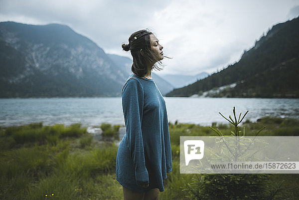 Junge Frau im blauen Pullover am See