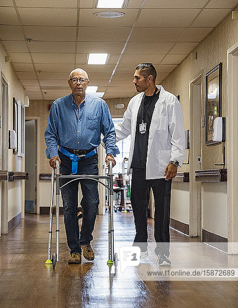 Arzt hilft älterem Mann bei der Benutzung einer Gehhilfe