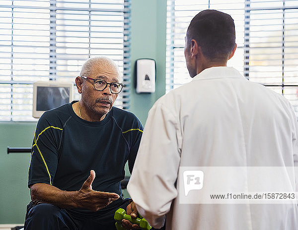 Älterer Mann im Gespräch mit dem Arzt im Rehabilitationszentrum