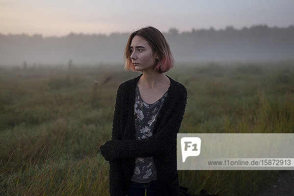 Young woman in field at sunset