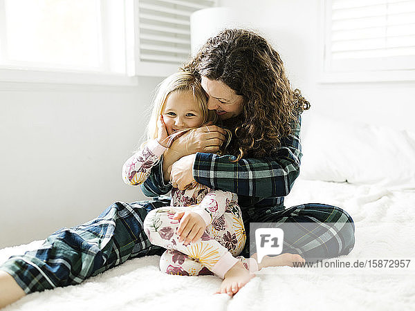 Mother and daughter hugging on bed