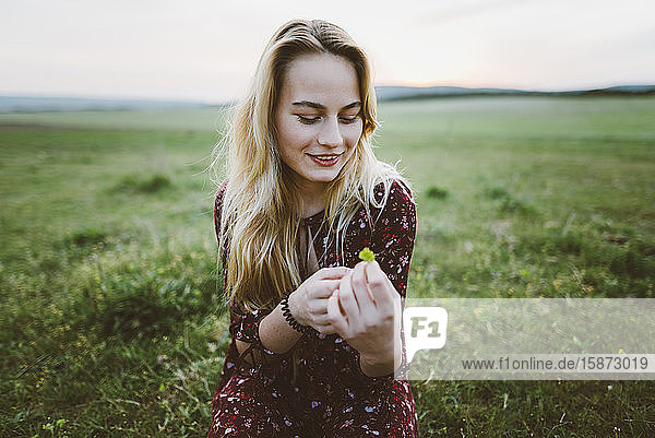 Lächelnde Frau mit Blume im Feld