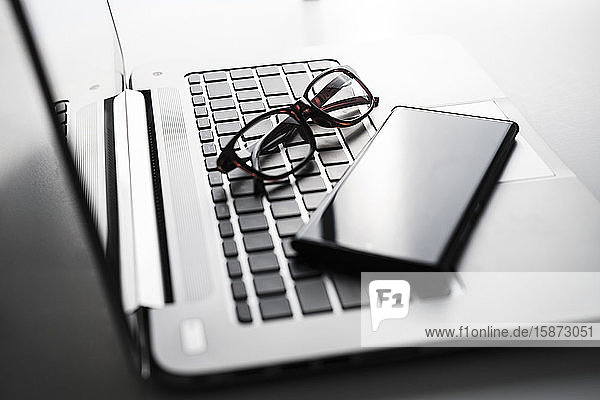 Smartphone und Brille auf der Laptop-Tastatur