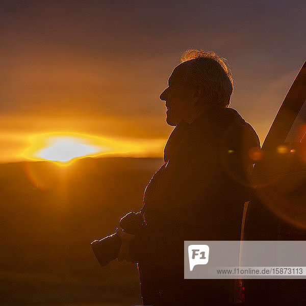 Älterer Mann mit Kamera bei Sonnenuntergang