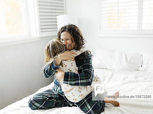 Mutter und Tochter umarmen sich auf dem Bett