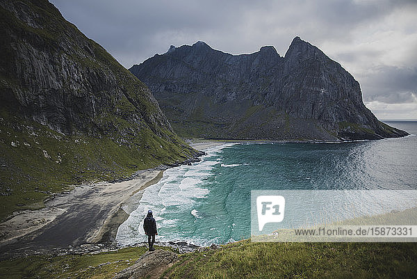 Mann steht auf einem Felsen am Strand von Kvalvika auf den Lofoten  Norwegen