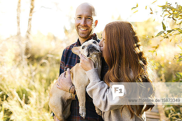 Couple with pet French bulldog in forest