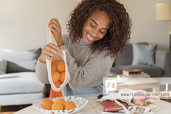 Lächelnde Frau legt Orangen in eine Schale