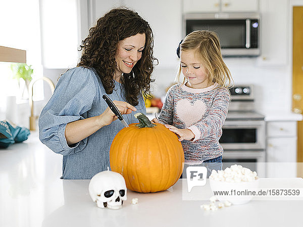 Mutter und Tochter schnitzen Kürbis für Halloween