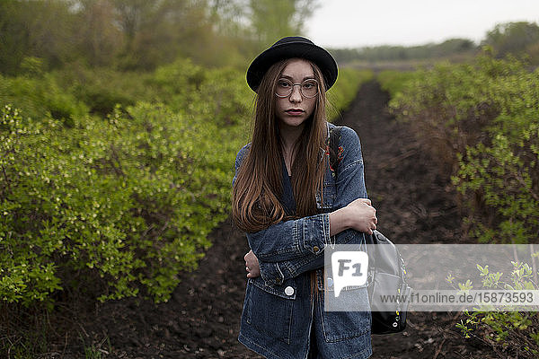 Young woman with denim jacket standing in field
