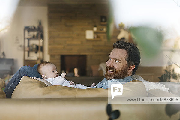 Father relaxing on sofa with baby son (2-3 months)