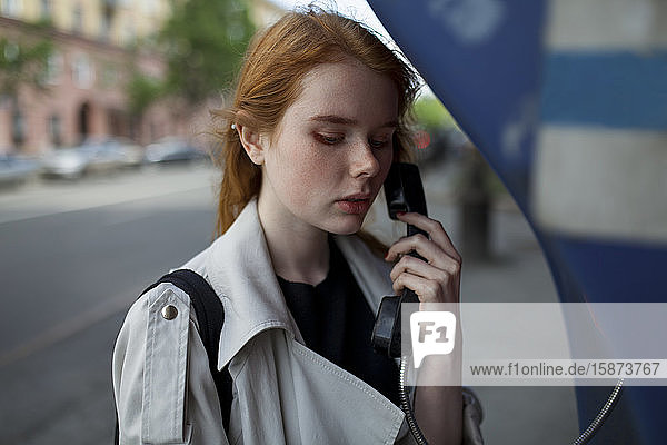 Junge Frau benutzt öffentliches Telefon