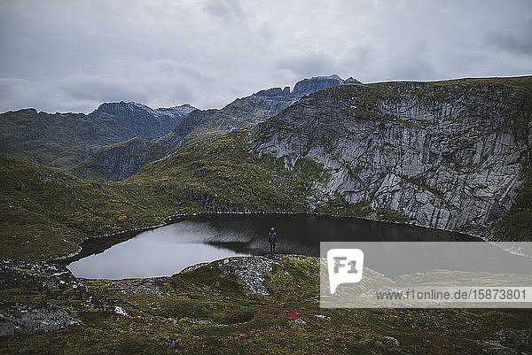 Mann steht auf einem Felsen am See auf den Lofoten  Norwegen