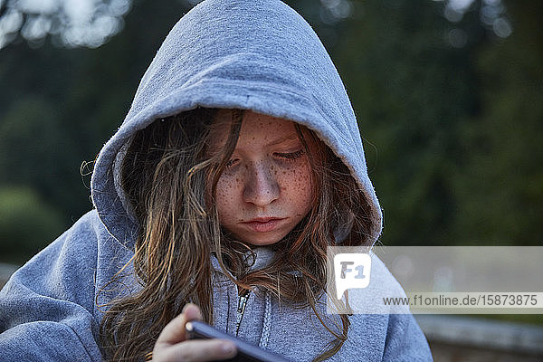 Girl in hoodie using phone