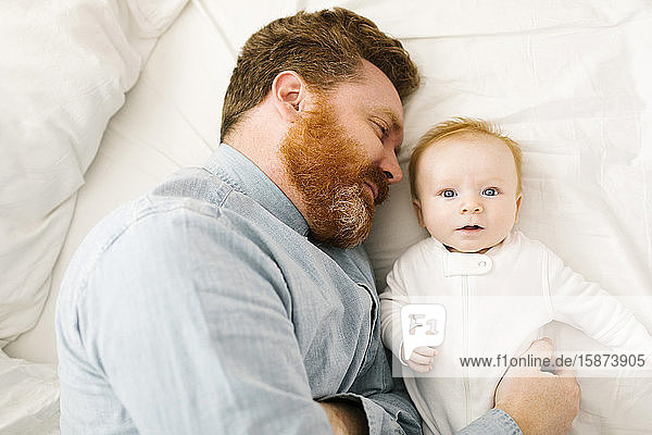 Vater und kleiner Junge (2-3 Monate) auf dem Bett liegend