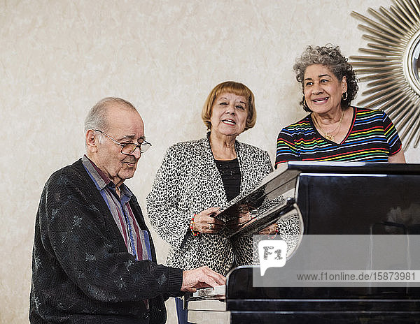 Ältere Frauen singen mit einem älteren Mann  der Klavier spielt