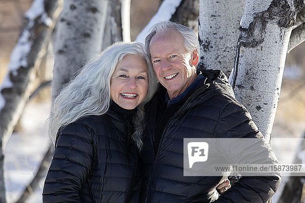 Smiling senior couple by tree