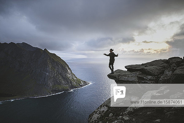 Mann steht auf einer Klippe am Berg Ryten auf den Lofoten  Norwegen