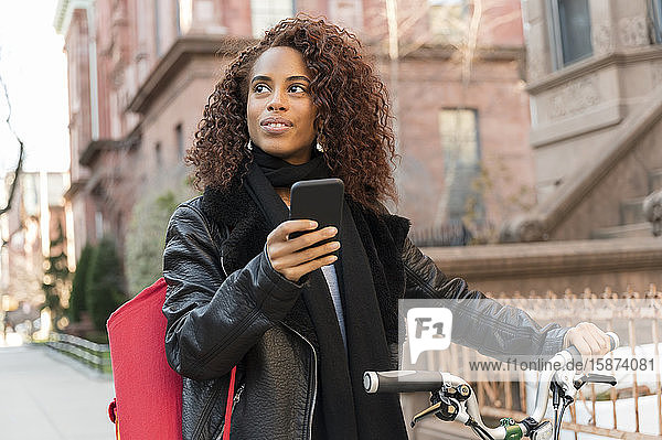 Frau mit Smartphone und Fahrrad in der Stadt