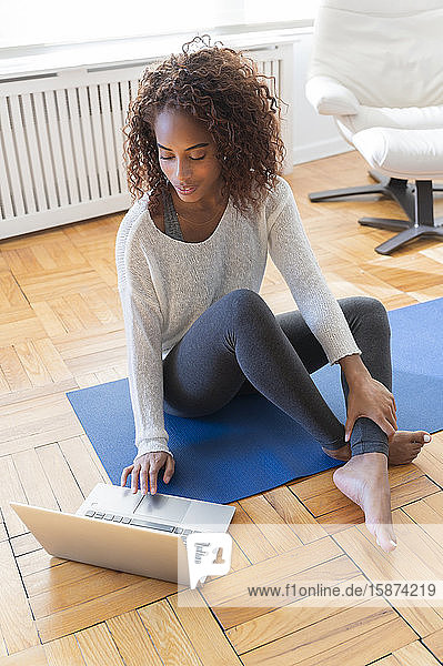 Frau benutzt Laptop auf Yogamatte