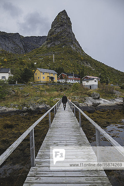 Mann geht auf einer Brücke an einer Klippe auf den Lofoten  Norwegen