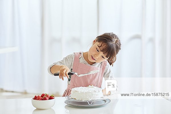 Junges glückliches Mädchen bereitet einen Kuchen in der Küche zu