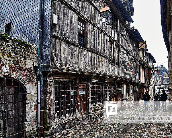 Typical half timbered Norman houses  People in the cobble streets Small butchers ( rue des Petits Boucherie ) of old town Honfleur.