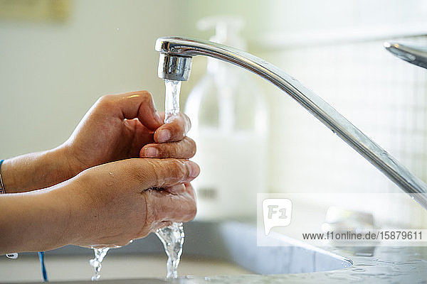 Woman washing hands with water in bathroom sink
