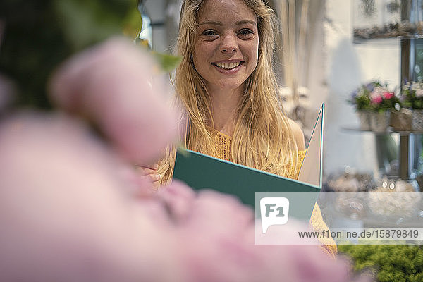 Young woman holding file in flower shop