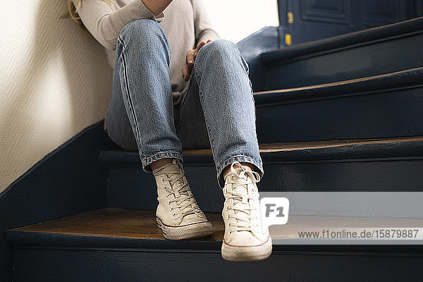 Tiefschnitt einer jungen Frau auf einer Treppe sitzend