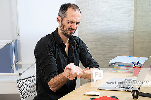 A man at his desk with hand and wrist pain.