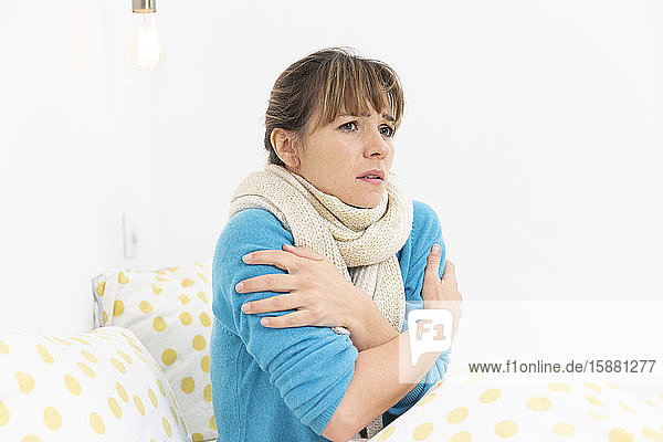 Eine junge Frau liegt im Bett und leidet an einer grippeähnlichen Erkrankung.