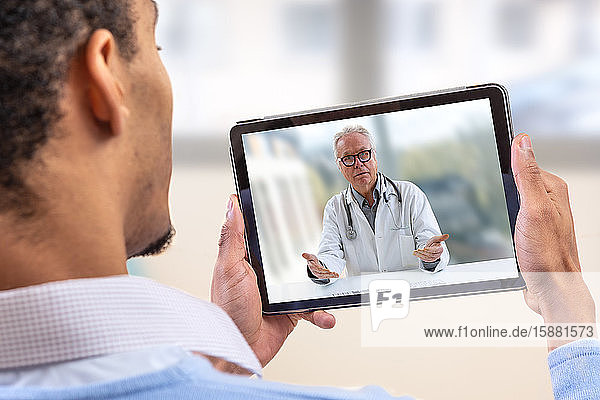 Telemedizin und Gesundheitskonzept mit einem jungen Mann und einem Arzt auf einem Computerbildschirm