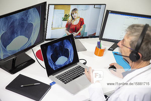 Ein Allgemeinmediziner während einer Videosprechstunde mit einer Frau  die eine Blasenaufnahme betrachtet.