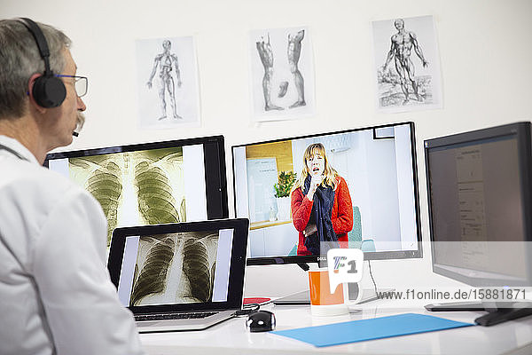 Ein Allgemeinmediziner betrachtet wÃ?hrend einer Videosprechstunde das RÃ¶ntgenbild einer Frau  die eine Lungeninfektion hat.