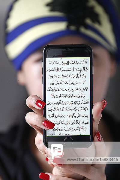 Frau mit einem digitalen Koran auf einem Smartphone.