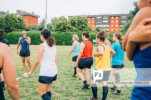 Eine Gruppe von Frauen beim Rugby-Training  vor ihnen steht der männliche Trainer.