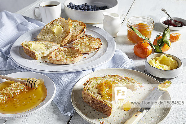 Plates of toast with butter and marmalade  dishes of honey  butter and jams.