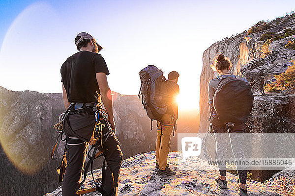 Eine Gruppe von Menschen auf einem Felsvorsprung  die einen Sonnenuntergang beobachten.