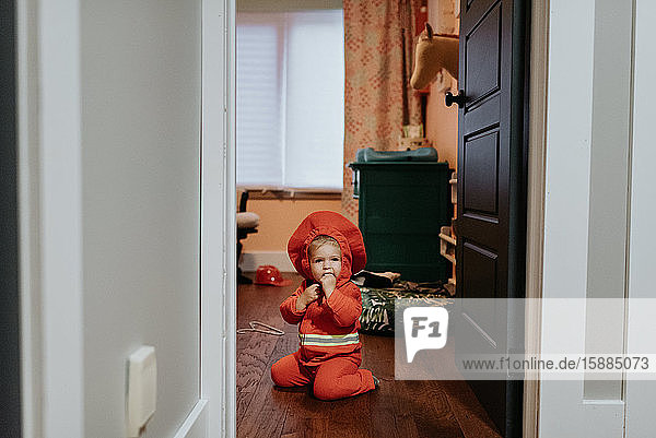 A child dressed as a firefighter kneeling on the floor.