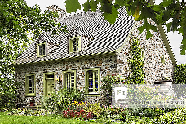 Exterior view of idyllic stone cottage with pretty garden in Canada.
