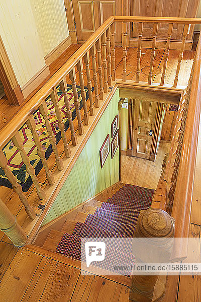High angle view of traditional wooden staircase with red runner and wooden railing.