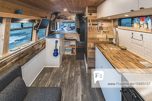 Interior of a campervan with a kitchen area in the foreground and sleeping area in the background.