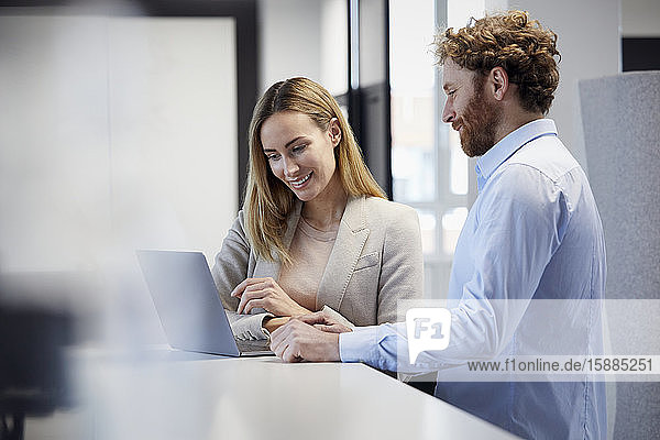 Businessman and businesswoman working together with laptop in office