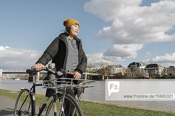 Frau mit Fahrrad am Flussufer  Frankfurt  Deutschland