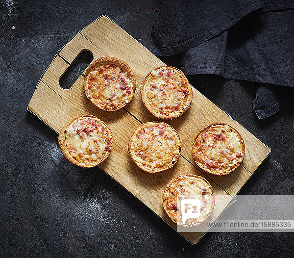 Schneidebrett und Mini-Pizzas mit Käse  Tomaten und Schinken