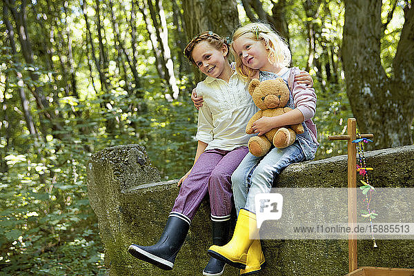 Children sitting on stone wall in forest
