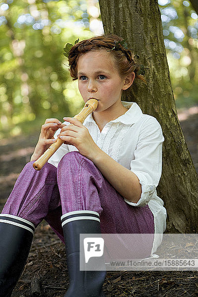 Portrait of girl playing recorder in forest