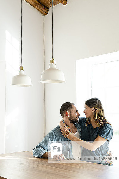 Affectionate couple in love relaxing at home and embracing at table